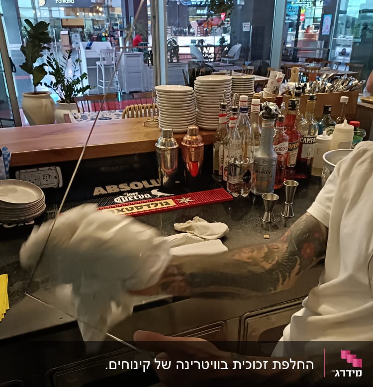 אדם מנקה זכוכית עם מטלית ליד בר